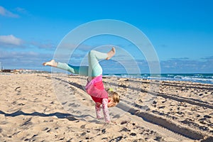 Little girl trying to do handstand on sandy Beach La Barrosa photo