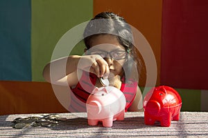 Little girl trying to put coins in her piggy bank, Pune, India