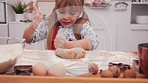 Little girl trying to stretch the cookie dough hitting it with her hands
