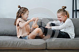 Little girl trying to tickle boy& x27;s foot, they both laugh.