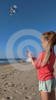 Little girl trying to untangle her knotted kite string on the beach