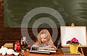 Little girl typewrite on vintage typewriter in school. Child typewrite keys on vintage machine in classroom