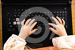 a little girl is typing on a laptop keyboard