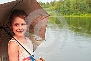 Little girl with an umbrella in cloudy day near the lake