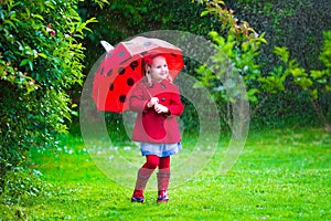 Little girl with umbrella playing in the rain