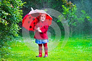 Little girl with umbrella playing in the rain