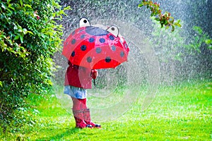 Little girl with umbrella playing in the rain