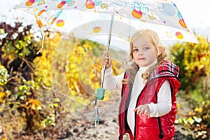 Little girl with umbrella in red vest outdoor