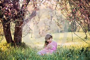 Little girl under blooming apple tree