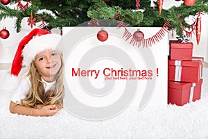 Little girl under the christmas tree with banner