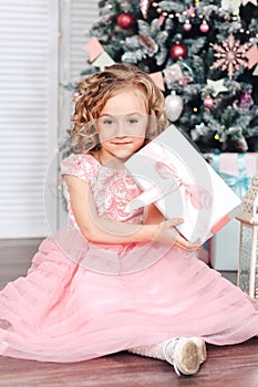 Little girl under the Christmas tree unpacking presents