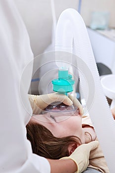 Little girl under general anesthesia. Breathing apparatus. Modern medicine and dentistry.Treatment of baby teeth.