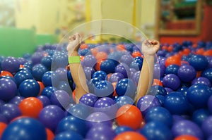 The little girl is under a plastic ball in Ball pit.