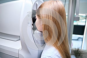 Little girl undergoing eye examination with automated refractor
