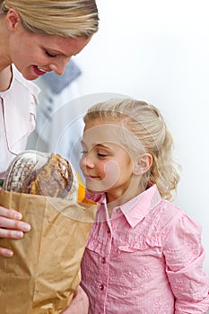 Little girl unpacking grocery bag with her mother