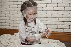 A little girl unpacks a box with Christmas decorations. New Year`s decorations. Christmas mood.