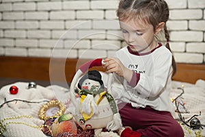 A little girl unpacks a box with Christmas decorations. New Year`s decorations. Christmas mood.