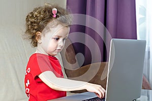 Little girl uses laptop. copy space. child and computer games, addiction.