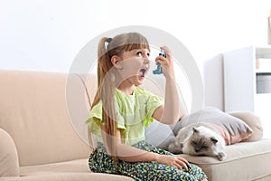 Little girl using asthma inhaler near cat at home