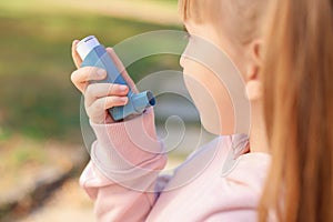 Little girl using asthma inhaler outdoors