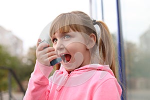 Little girl using asthma inhaler outdoors