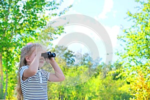 Little girl using binoculars in the forest. Exploring the world. Outdoor activities