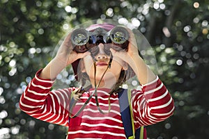 Little girl using binoculars in the forest