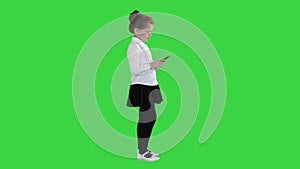 Little girl using cell smart phone on a green screen, chroma key.