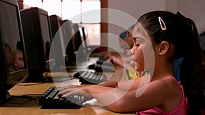 Little girl using computer in classroom in school