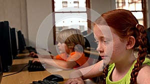 Little girl using computer in classroom in school