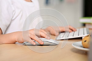 Little girl using computer at table in room, closeup. Internet addiction