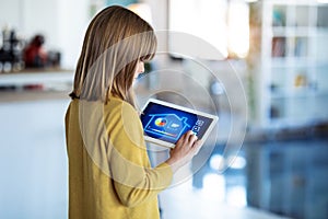 Little girl using a domotic system with her digital tablet while standing at home