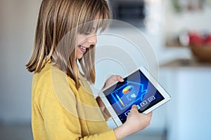 Little girl using a domotic system with her digital tablet while standing at home