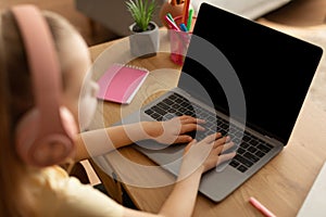 Little Girl Using Laptop Computer With Blank Screen Learning Indoors