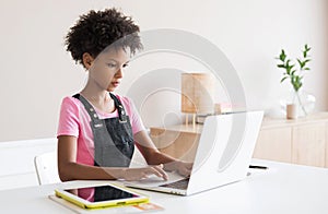 Little girl using laptop at home, child working online on computer indoor, Children lifestyle, distance education concept