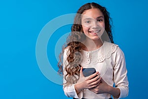 Little girl using mobile phone.against blue background