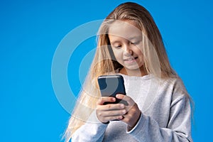 Little girl using mobile phone.against blue background