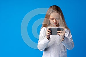 Little girl using mobile phone.against blue background