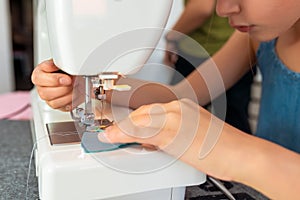 Little girl using a sewing machine to sew on a piece of fabric. Creative tailoring workshops for children