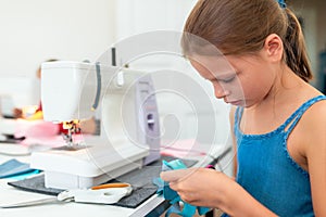 Little girl using a sewing machine to sew on a piece of fabric. Creative tailoring workshops for children