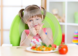 Little girl with vegetables food showing thumb up