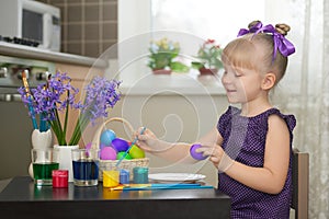 Pequeno en púrpura ropa decorando pascua de resurrección huevos 