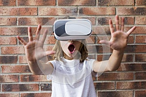 Little girl with virtual reality headset. Innovation technology and education concept. Brick background