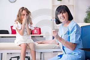 Little girl visiting old female doctor