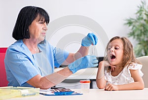 Little girl visiting old female doctor