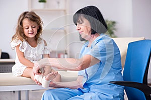 Little girl visiting old female doctor