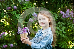 Little girl with waffle ice cream cone filled with lilac flowers in her hands