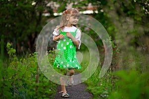 Little girl walk in green garden in summer day