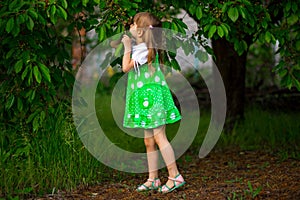 Little girl walk in green garden in summer day