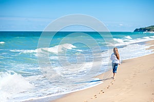 Little girl walking along the seashore on a sunny day